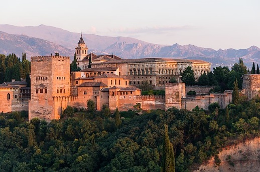 A large building with trees in the background with Alhambra in the background